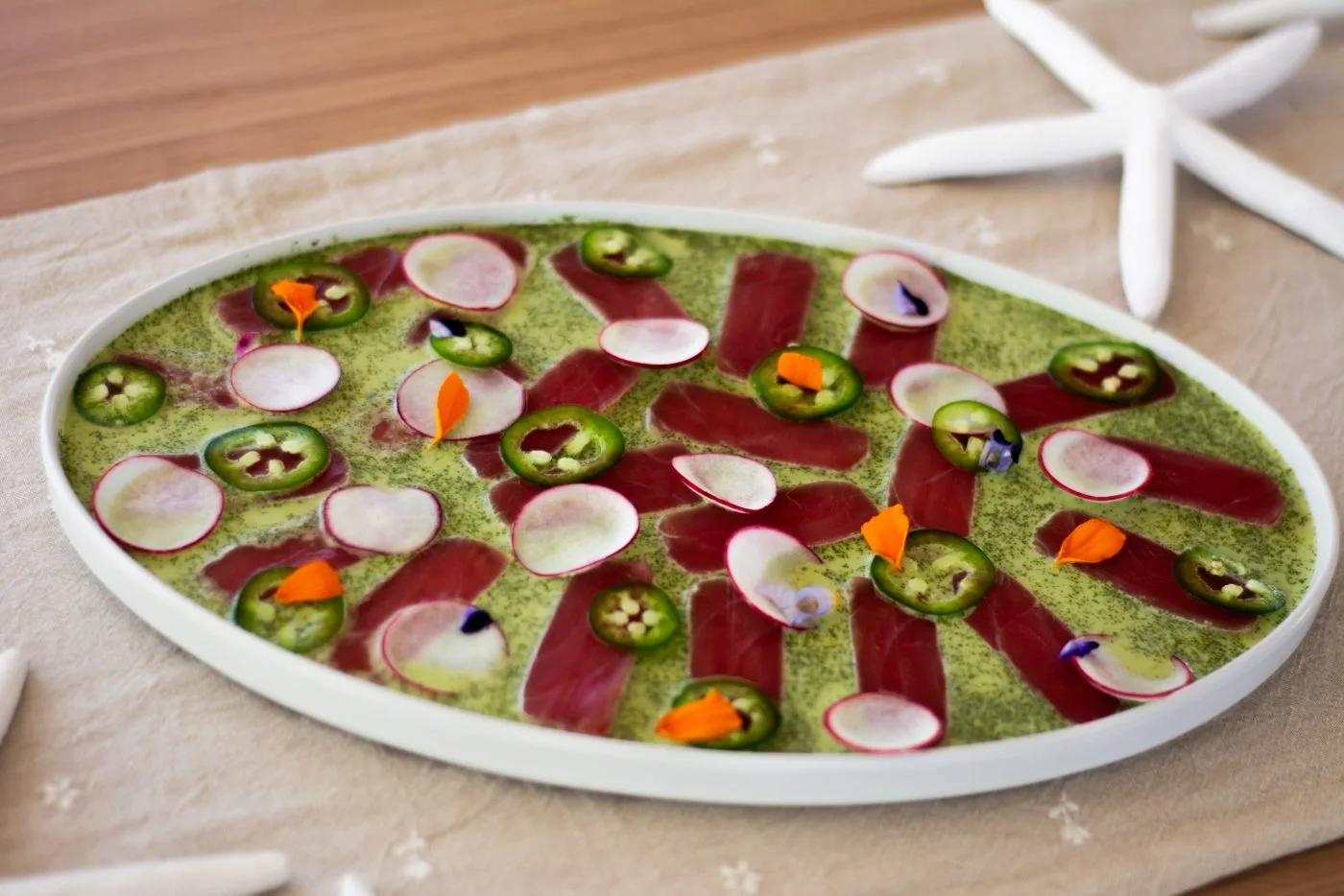 Tuna tataki on green herb sauce with watermelon radish