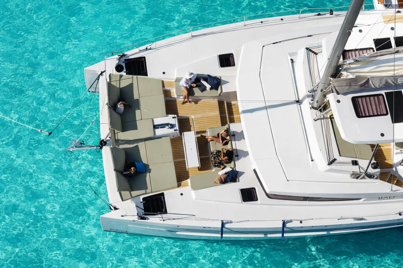 Aerial view of Allegra's forward cockpit lounge — guests relaxing on sun pads over turquoise water