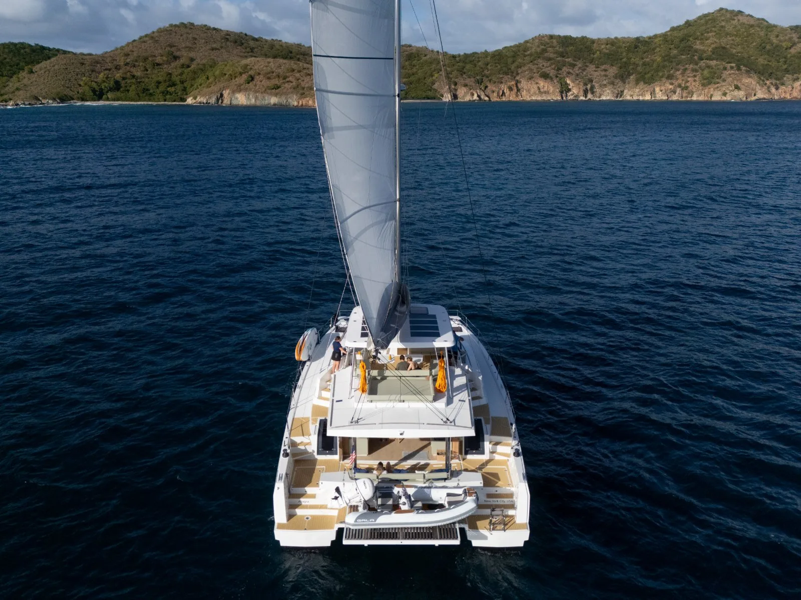 Allegra sailing toward a remote BVI cove — aerial stern view