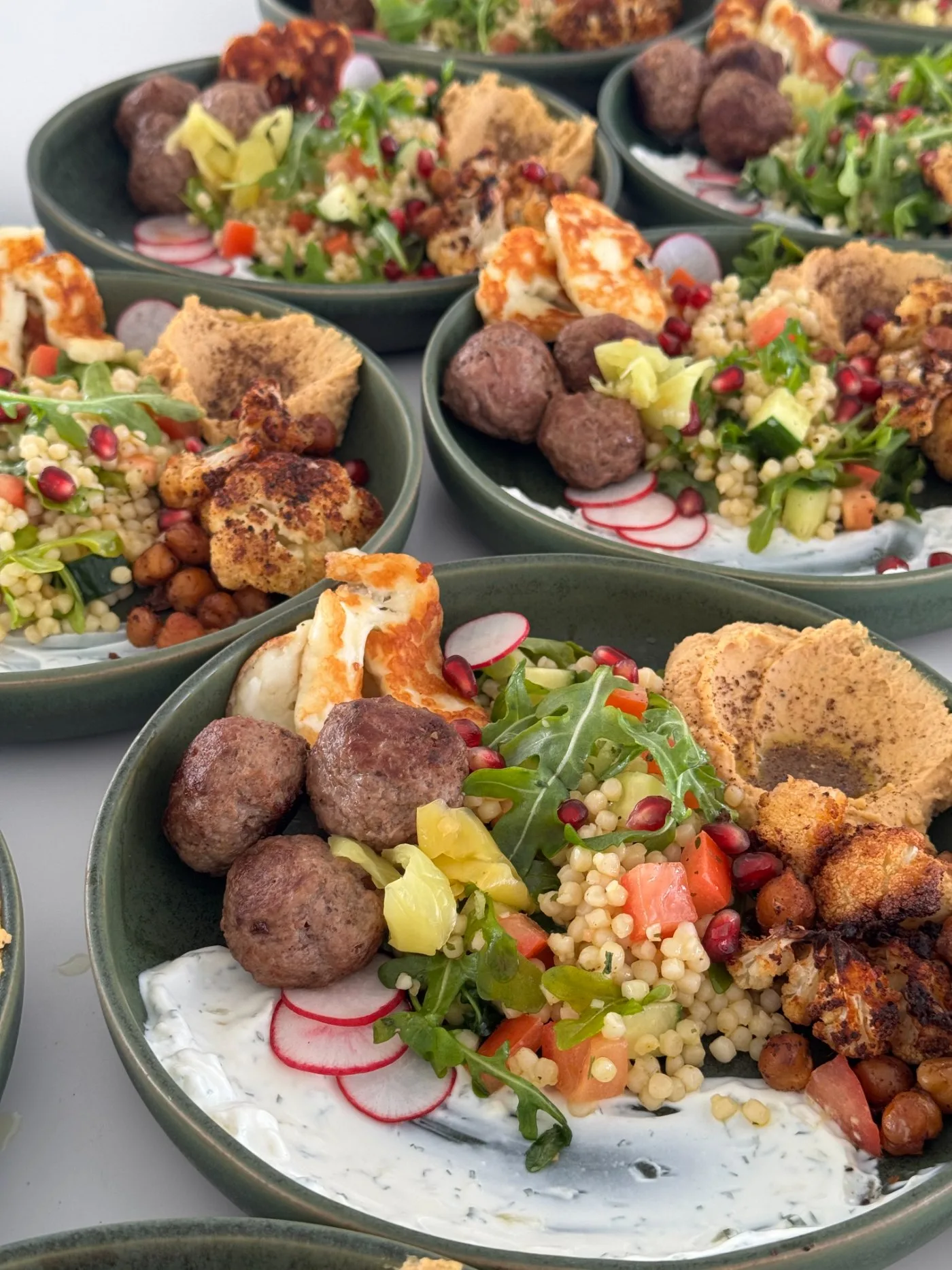 Mezze bowls — lamb kofta, halloumi, hummus, tabbouleh, pomegranate
