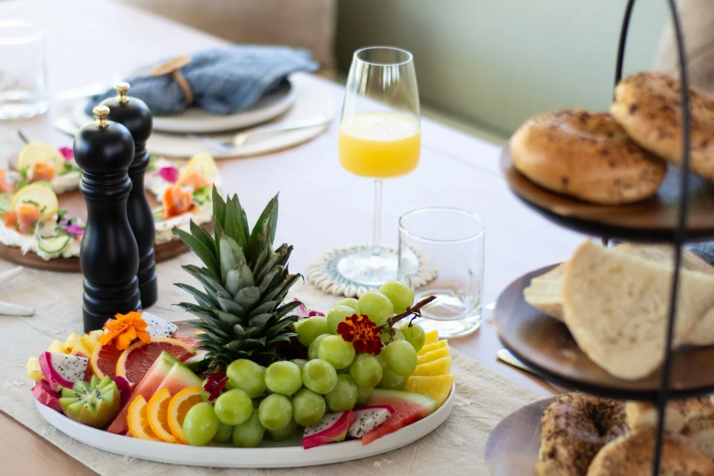 Breakfast spread with fresh fruit platter, bagels, and mimosas