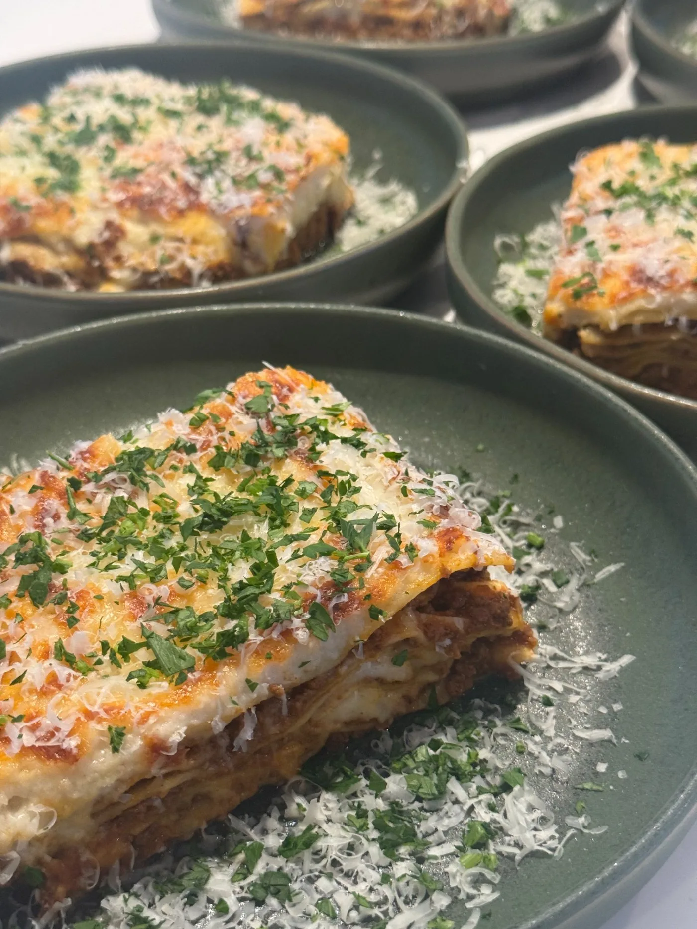 Slow-baked lasagne plated with parsley and parmesan