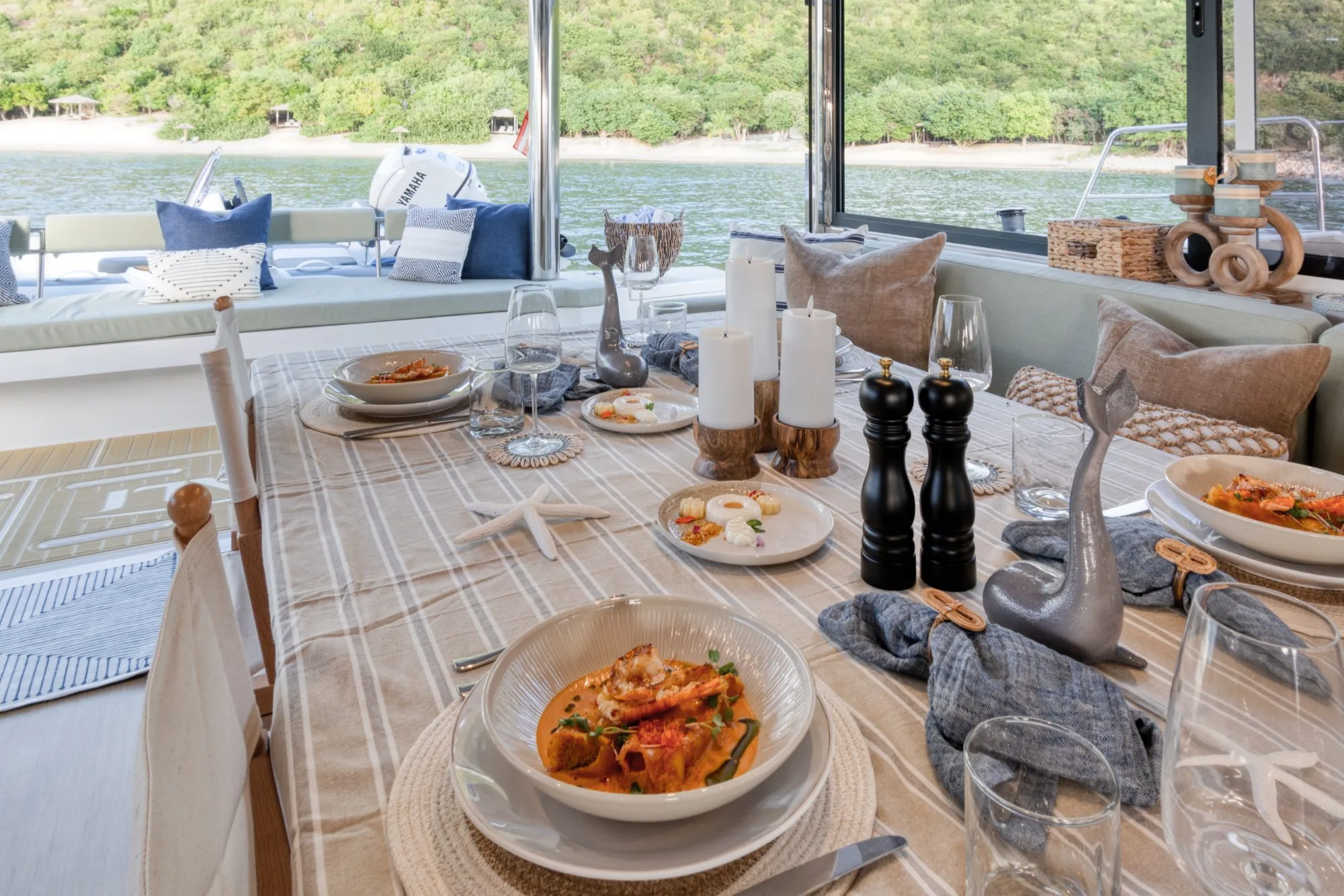 Dinner service on Allegra's aft deck — table set against a quiet cove